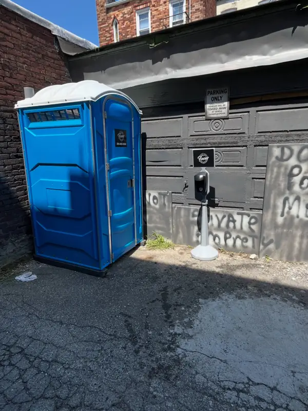 Blue portable toilet beside a building on a jobsite