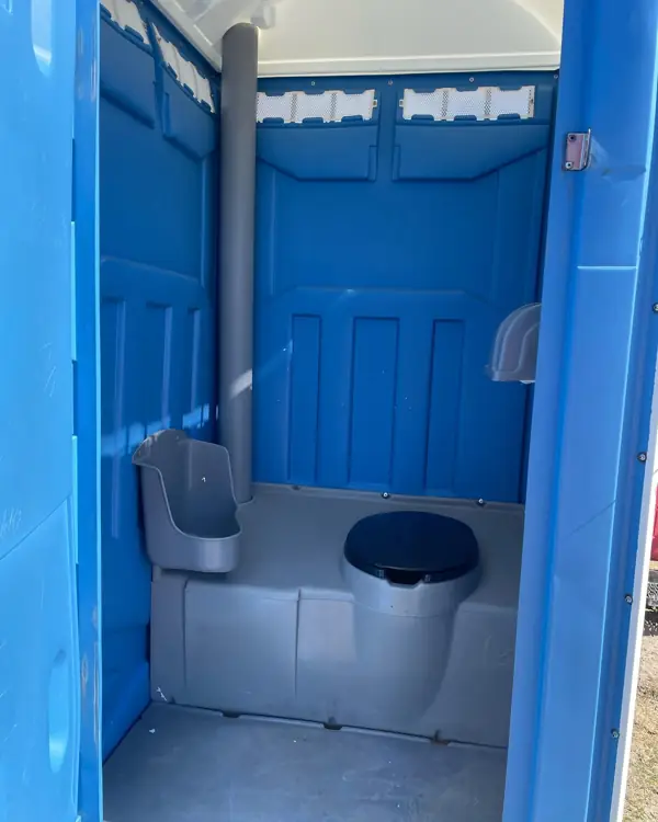 Clean interior of a blue portable toilet showing the seat, urinal and vent pipe
